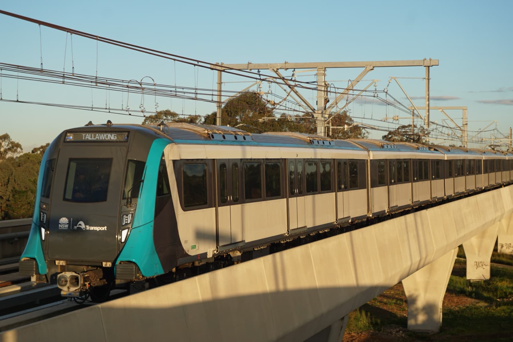 Sydney Metro train on elevated track at sunset